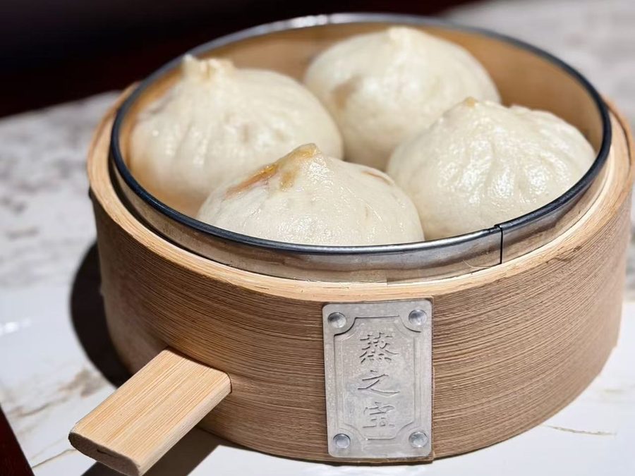 Wok Hei Bao, four pleated steamed buns in a bamboo steamer