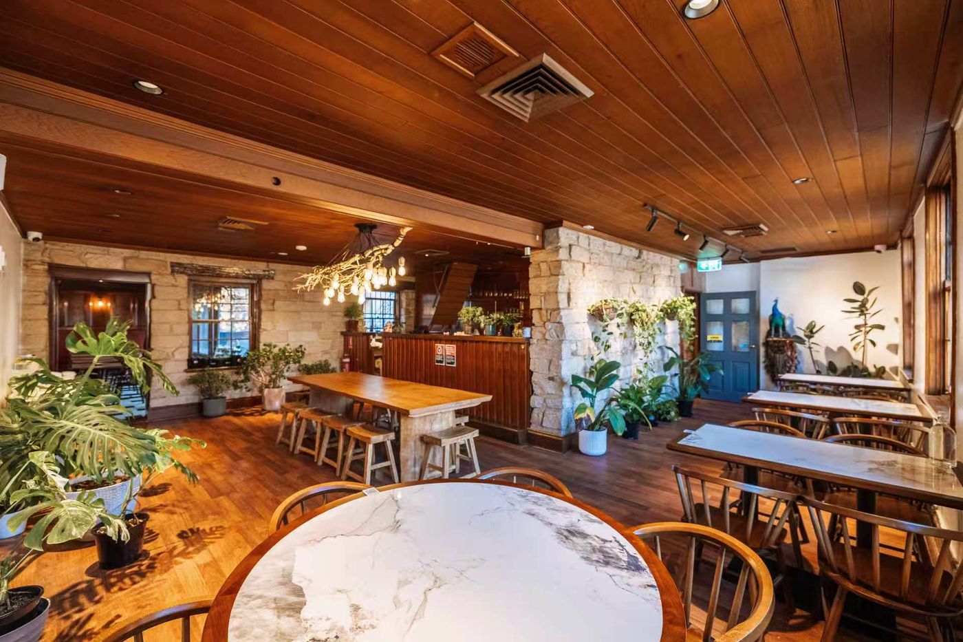 The main dining room with timber ceiling, sandstone walls and the bar beyond