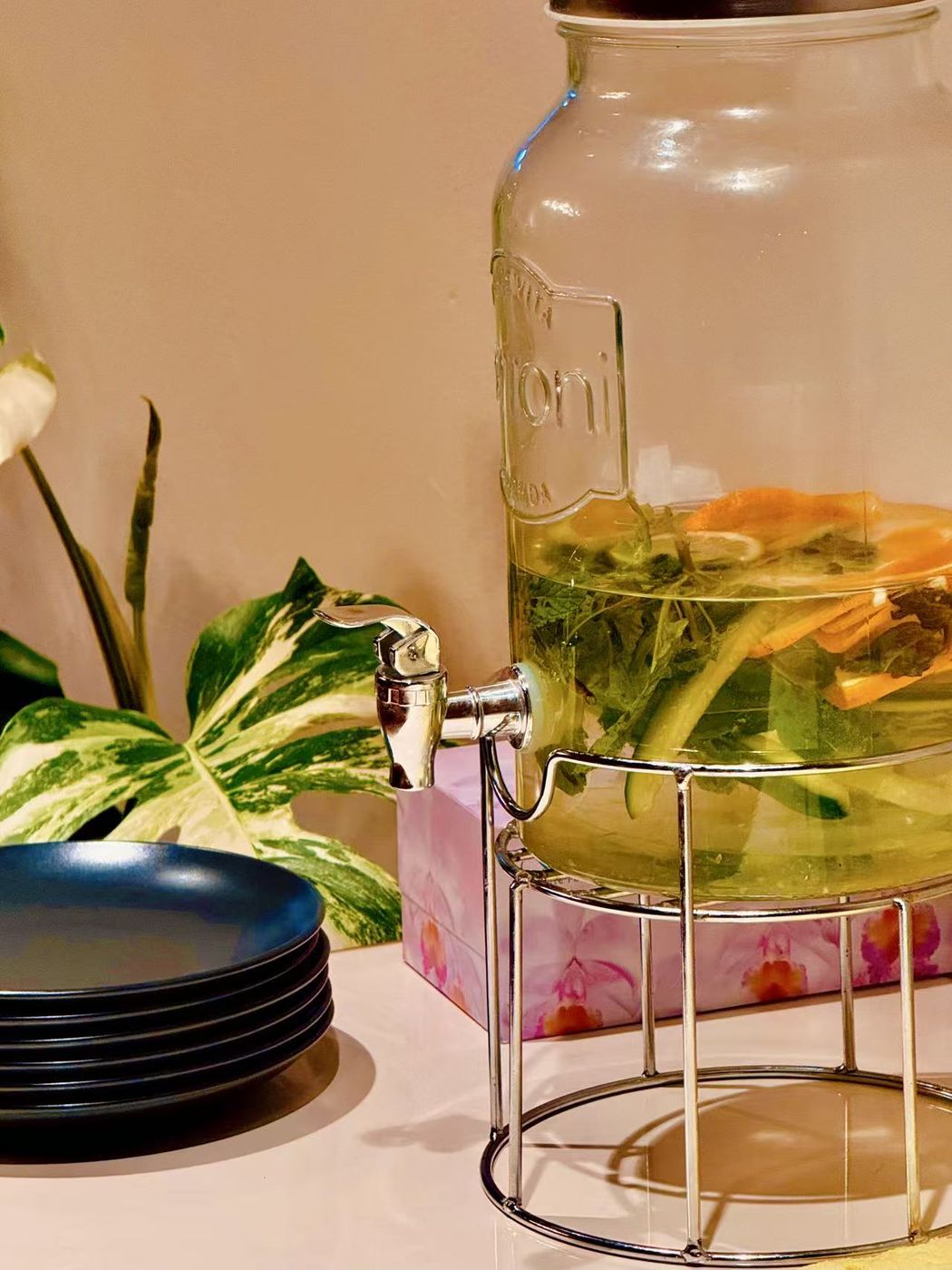 A glass dispenser of house-made herbal infusion with mint and citrus