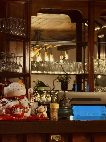 Lucky cats, glassware and warm lamplight on the bar